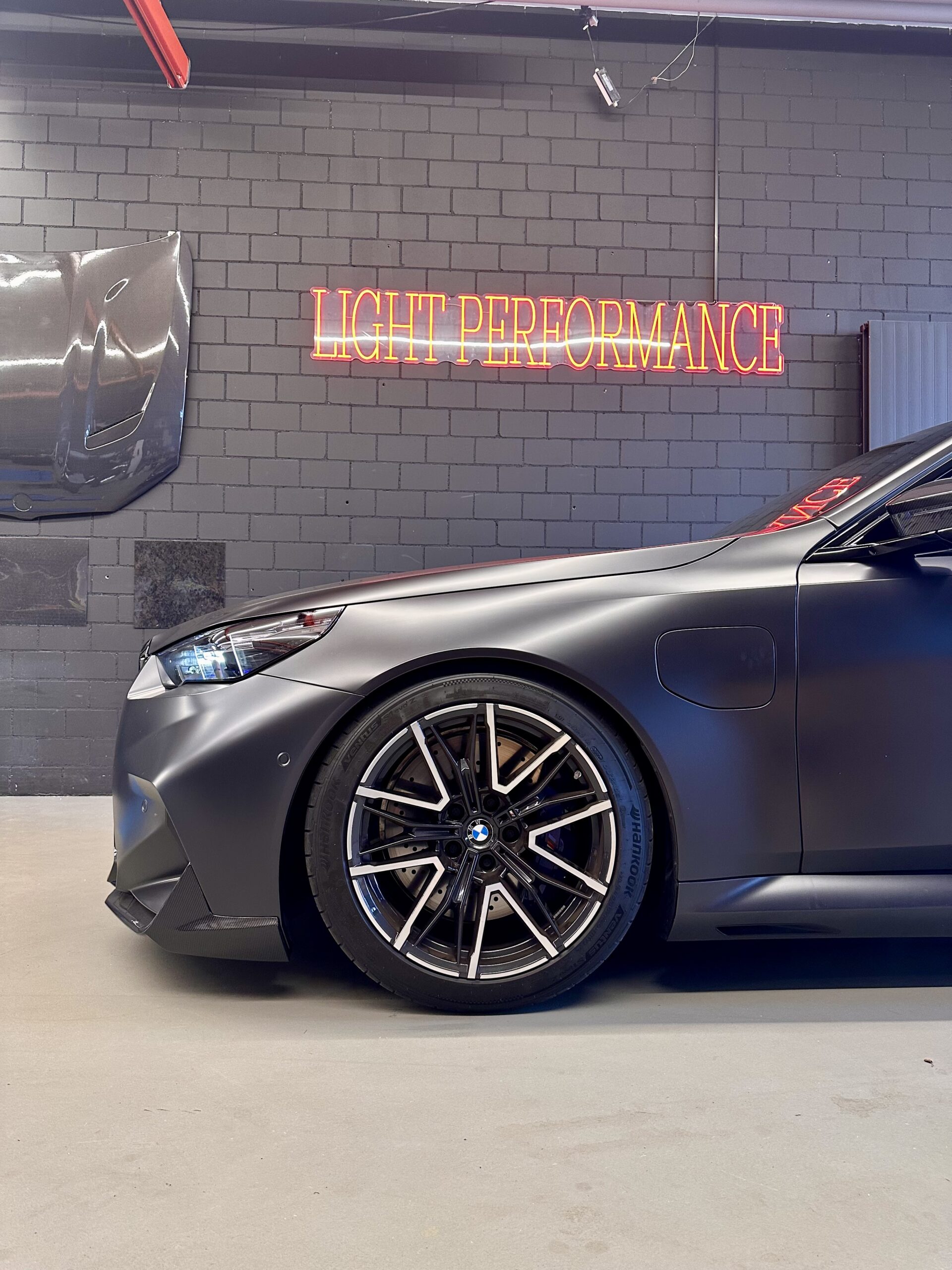 Mattschwarzes Auto vor Neonlichtwand