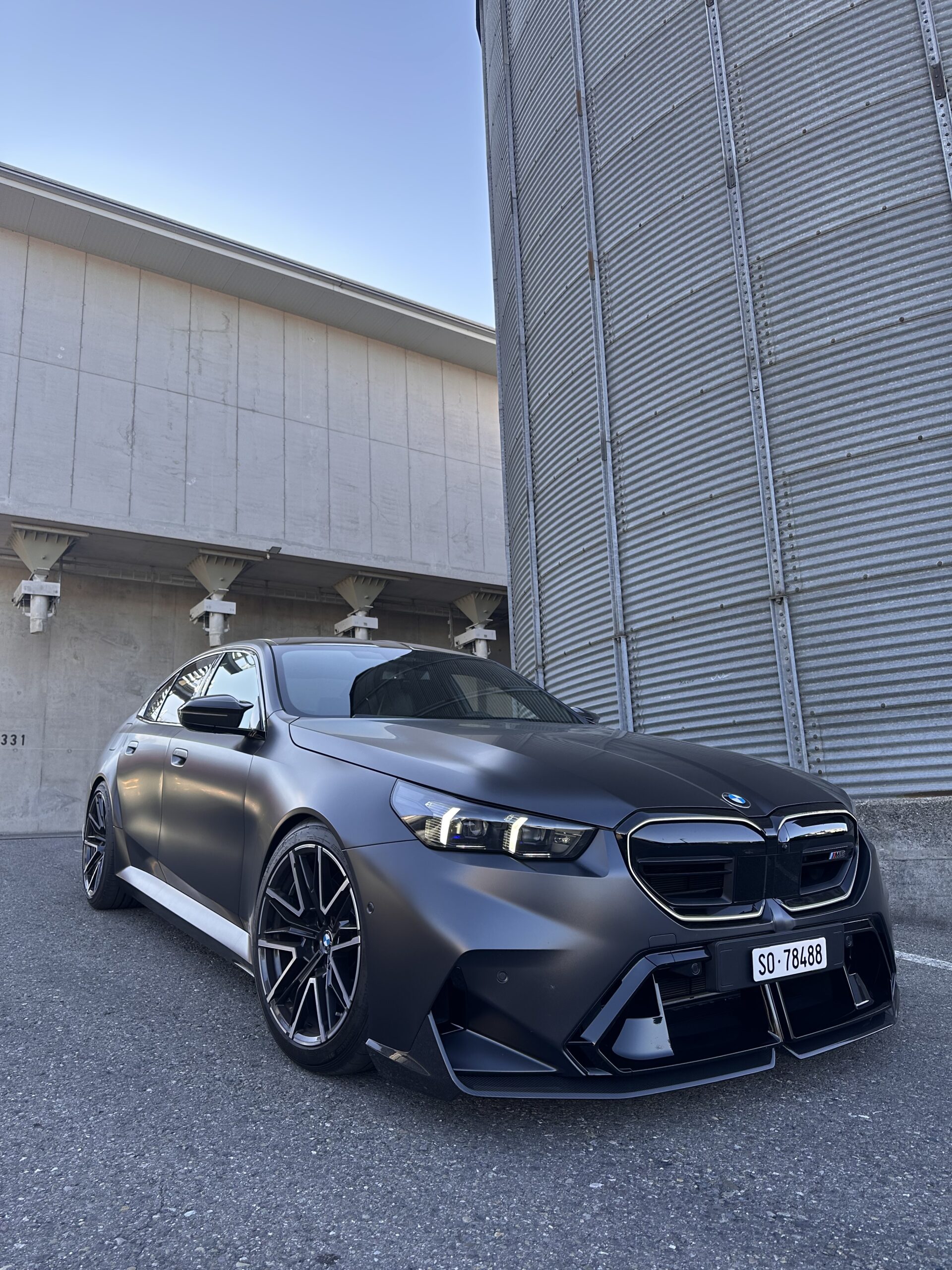 Schwarzes Auto vor einem Industriegebäude.