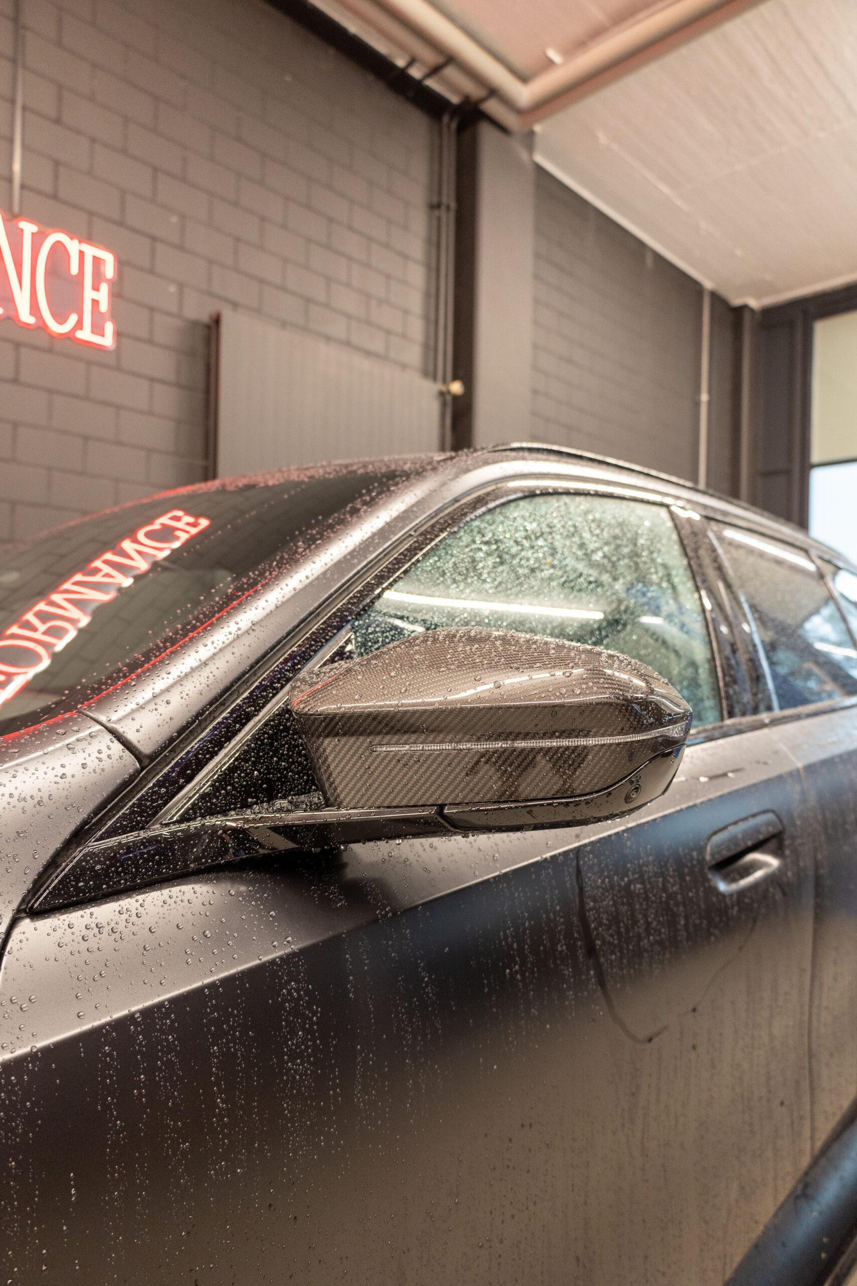 Auto mit Regentropfen bedeckt, Garage im Hintergrund.