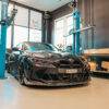 Schwarzes Auto in Werkstatt unter Hebebühne.